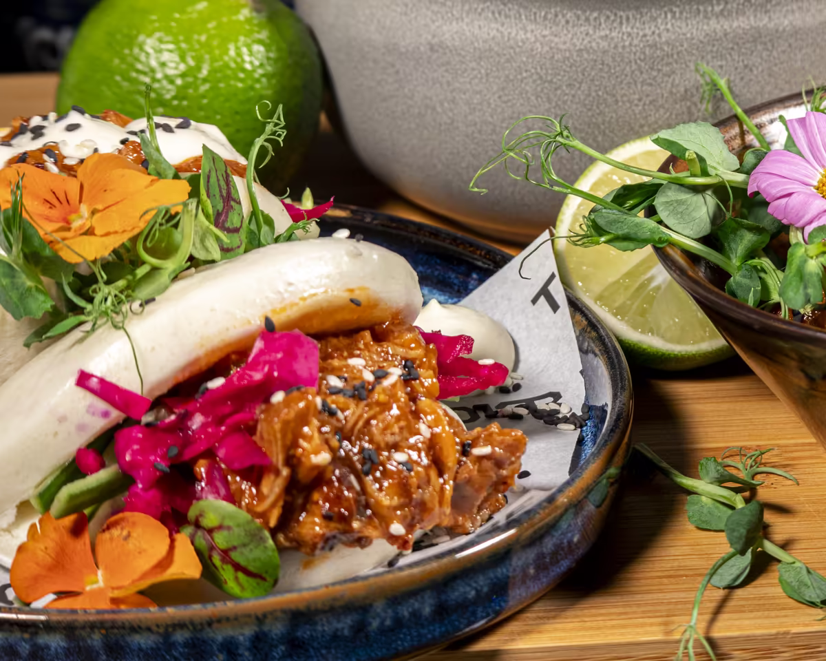 BBQ pulled pork bao buns with pickled red cabbage and edible flowers